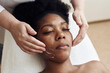 © etonastenka - A young black woman lies in the beautician's office and relaxes from gentle touches and toning massage. The concept of spa treatments