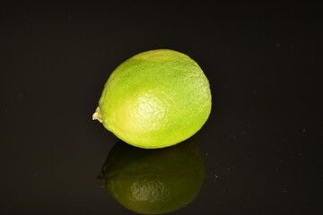 One green ripe lime, on a black background.