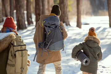 Wall Mural - Backs of young man with backpack and little girl moving towards country house