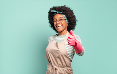 Wall Mural - black afro woman feeling proud, carefree, confident and happy, smiling positively with thumbs up. housekeeping concept.. household concept