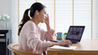 © ChayTee - Back rear view young asian woman employee work from home using computer notebook videocall meeting conference angry annoy with low poor unreliable internet wifi connection problem issue outage.