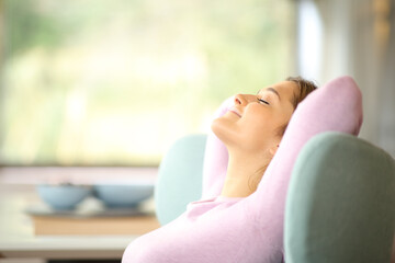 Wall Mural - Side view of a woman resting and relaxing on a couch at home