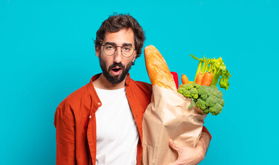 Sticker - young bearded man looking very shocked or surprised, staring with open mouth saying wow and holding a vegetables bag