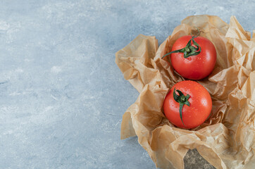 Two fresh whole tomatoes on a parchment paper