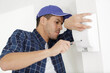 © auremar - male electrician installing security system door sensor on wall