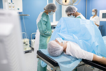 Poster - Male patient lying on operating table while two surgeons preparing for operation