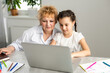 © Angelov - Grandmother teaching to granddaughter with the help of the computer. Worried old teacher helping girl studying and doing homework on laptop at home, private lesson