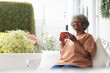 © Wavebreak Media - Thoughtful african american senior woman holding coffee cup smiling while sitting on porch of the ho