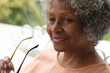© Wavebreak Media - Portrait of african american senior woman holding glasses smiling while sitting on porch