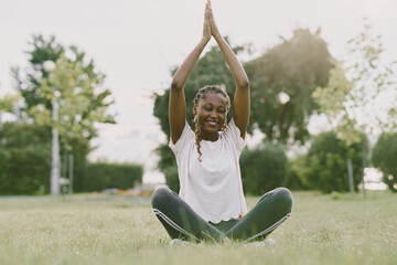 Healthy young african woman outdoors in morning park. Girl doing yoga.