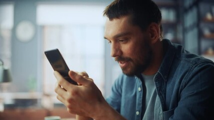 Poster - Handsome Caucasian Man Using Smartphone in Cozy Living Room at Home. Freelancer Working From Home. He's Browsing the Internet and Checking Videos on Social Networks and Having Fun.
