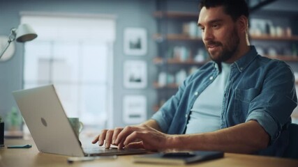 Poster - Handsome Caucasian Man Working on Laptop Computer while Sitting on a Sofa Couch in Stylish Cozy Living Room. Freelancer Working From Home. Browsing Internet, Using Social Networks, Having Fun.
