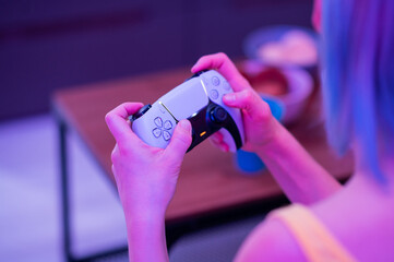 Girl with next gen controller in her hands playing games at home.