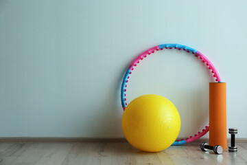 Canvas Print - Hula hoop, fitness ball, mat and dumbbells near light wall in gym. Space for text