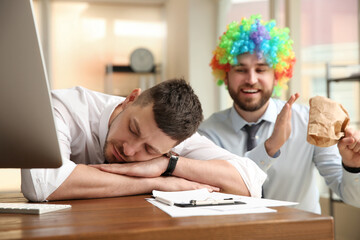 Sticker - Young man popping paper bag behind his sleeping colleague in office. Funny joke