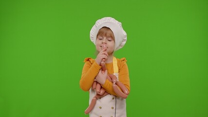 Wall Mural - Child girl kid dressed as professional cook chef stay with sausages, fooling around, making faces, showing thumbs up on chroma key background. Nutrition, cooking school, education, food. Fun and humor