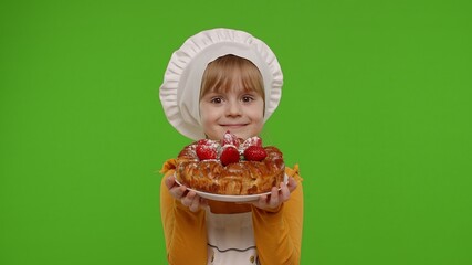 Wall Mural - Portrait of little child girl kid dressed as professional cook chef baker with tasty strawberry pie, looking at camera on chroma key background. Concept of sweet nutrition food, cooking school