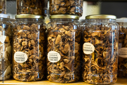 Dried red and black chanterelles, champignons, fairy-ring mushrooms in jars at grocery store counter