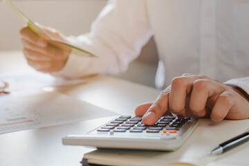 Close up hand of stress young asian businessman,male is pressing a calculator to calculate tax income and expenses, bills, credit card for payment or payday at home, office.Financial, finance concept.