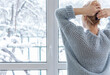 © Дворецкая Таня - A woman looks out of the window at the snow-covered outdoors
