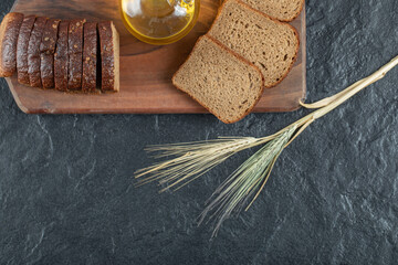 Wall Mural - Slices of brown bread with wheat on a wooden board