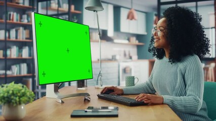 Aufkleber - Latina Female Specialist Working on Desktop Computer with Green Screen Mock Up Display at Home Living Room while Sitting at a Table. Freelancer Female Chatting Over the Internet on Social Networks.