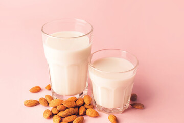 Glasses of tasty almond milk on color background