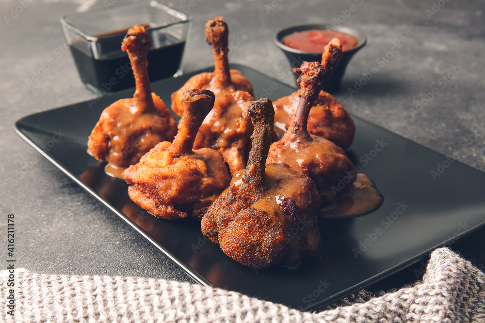 Plate with tasty chicken lollipops on dark background
