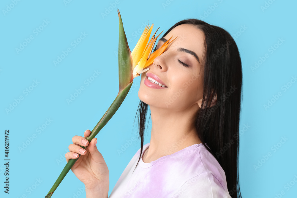 Beautiful young woman with flower on color background