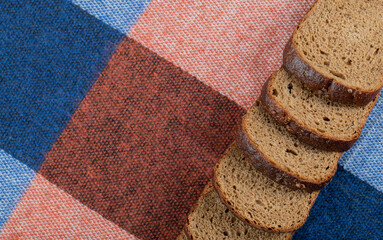 Wall Mural - Slices of fresh brown bread on a tablecloth