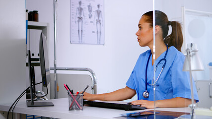 Wall Mural - Medical woman nurse typing on computer patient health report, sitting in hospital office. Healthcare physician in medicine uniform writing treatments making appointments checking registration.