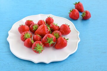 Fresh organic strawberry on white plate on blue background