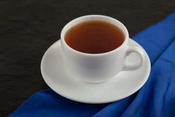 A white cup of hot tea on a black background