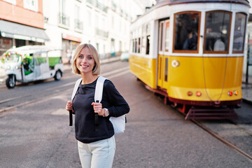 Wall Mural - Traveling by Portugal. Happy young woman with rucksack walking by streets in Lisbon.