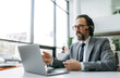 © Kateryna - Senior adult business male in headset is sitting at the desk, using laptop, communicate with clients. Caucasian grey-haired manager is consulting people, support service concept