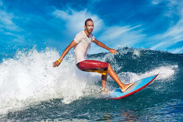 Male surfer on a blue wave at sunny day