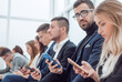 © ASDF - group of young business people looking at their smartphone screens.