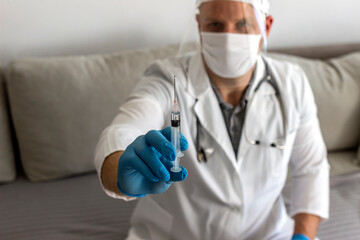 Wall Mural - Portrait of a doctor, researcher or scientist in blue glove holding vaccine and syringe with needle, vaccination for patient. Young doctor holding injection on gray background. Focus on a syringe.