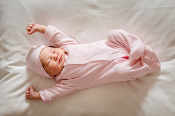 cute little girl of 5 days in a pink jumpsuit lie on plaid and stretches in a dream in full height