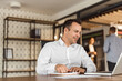 © bnenin - Businessman looking at laptop while sitting at office desk, portrait.