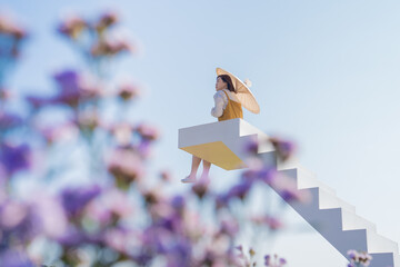 asian woman relax and hold umbella on white stair in flower garden on springtime vacation