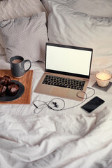 Wall Mural - Breakfast in bed: a wooden tray with granola and cup of cocoa with a laptop on background.