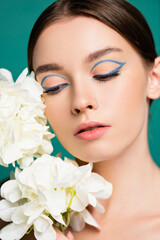 portrait of young woman with creative makeup near white peonies isolated on green