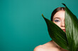 © LIGHTFIELD STUDIOS - sensual young woman looking at camera near wet leaf isolated on green