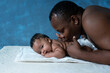 Father lying on bed and kiss his baby daughter, 4 mouth baby, man is not wearing a shirt