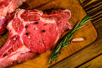 Wall Mural - Raw ribeye steak, spices, rosemary and garlic on cutting board. Top view