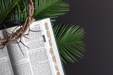 Canvas Print - palm fronds, open bible and crown of thorns on black background