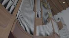 Camera Pans Along A Large Organ In The Gallery Of A Church, Many Organ Pipes In The Front