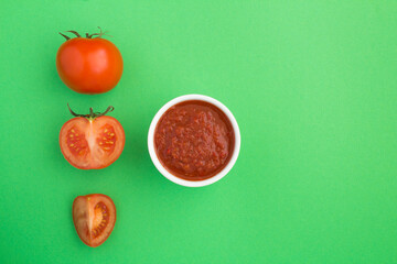 Top view of homemade tomato ketchup and tomato on the green background