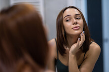 Beauty Skin Care. Young Beautiful Woman Touching Her Face Before The Mirror, Enjoying Her Clean Skin. Pretty Woman Touching Her Cheek And Smiling. Perfect Pure Skin. Fresh Clean Skin. Skincare